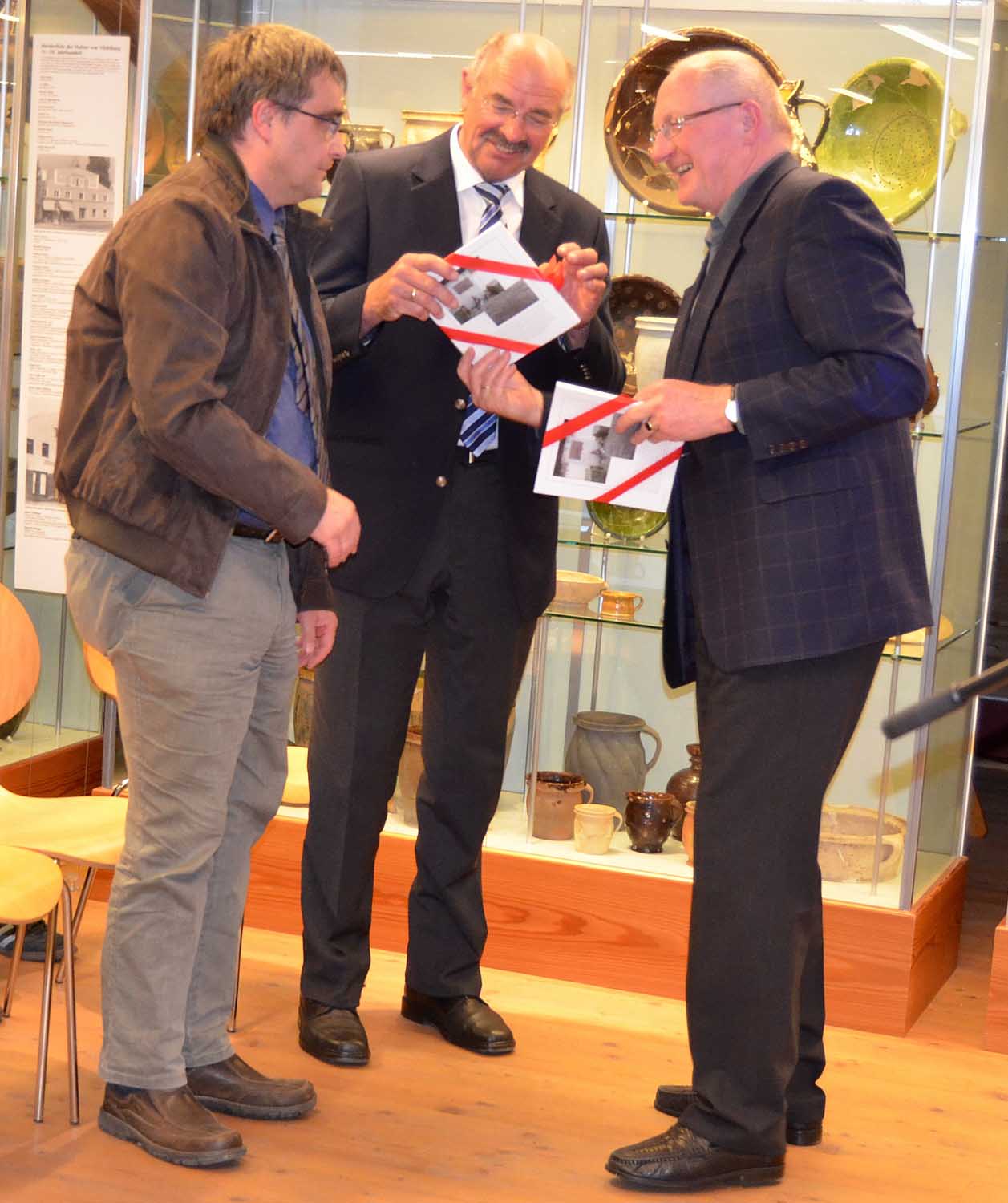 Pfarrer Michael Lenk (links) und Landrat Alfons Satzl erhalten die ersten Exemplare der Museumsschrift